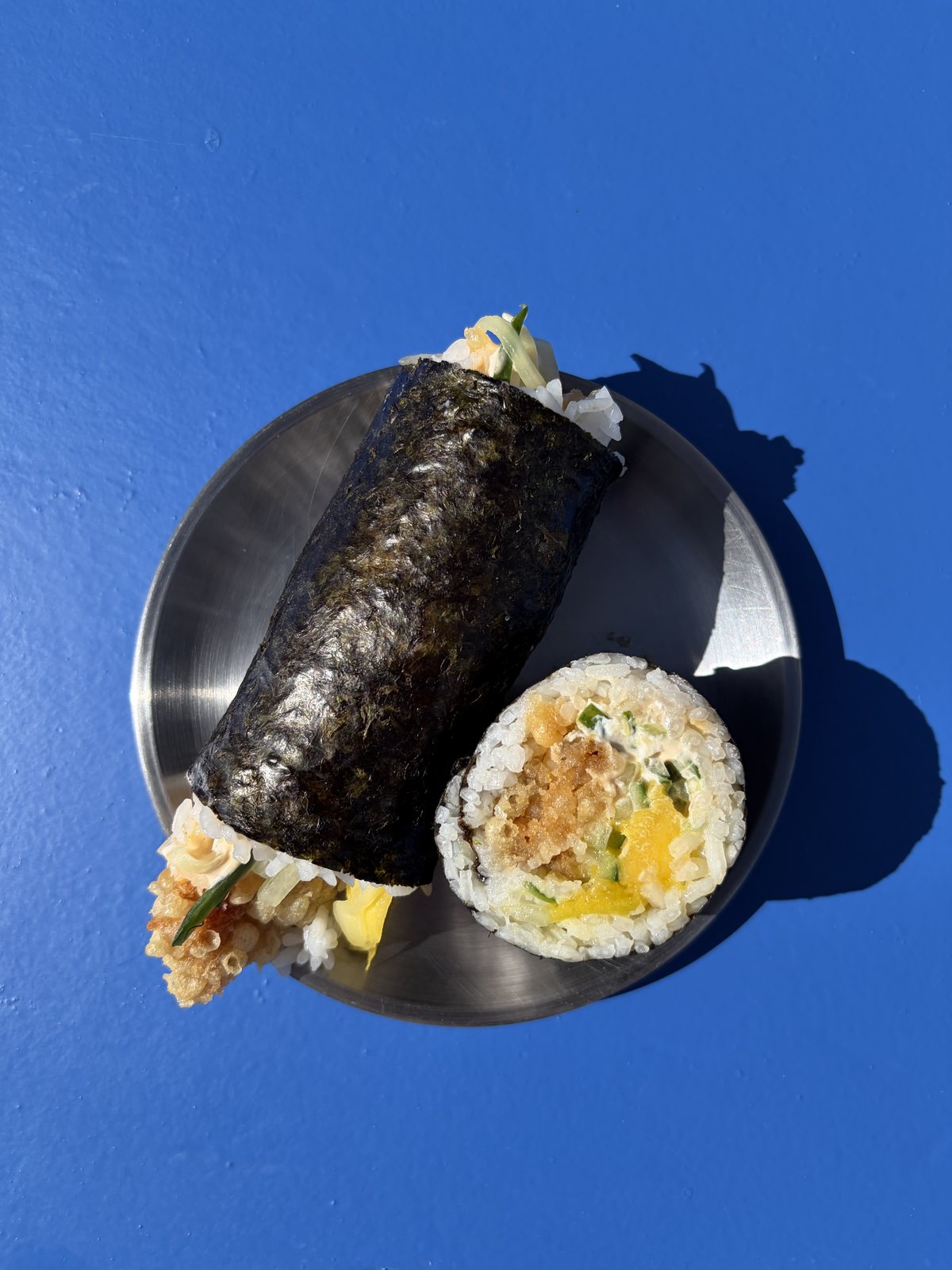 Roll japonés de katsu crujiente cortado, sobre fondo azul